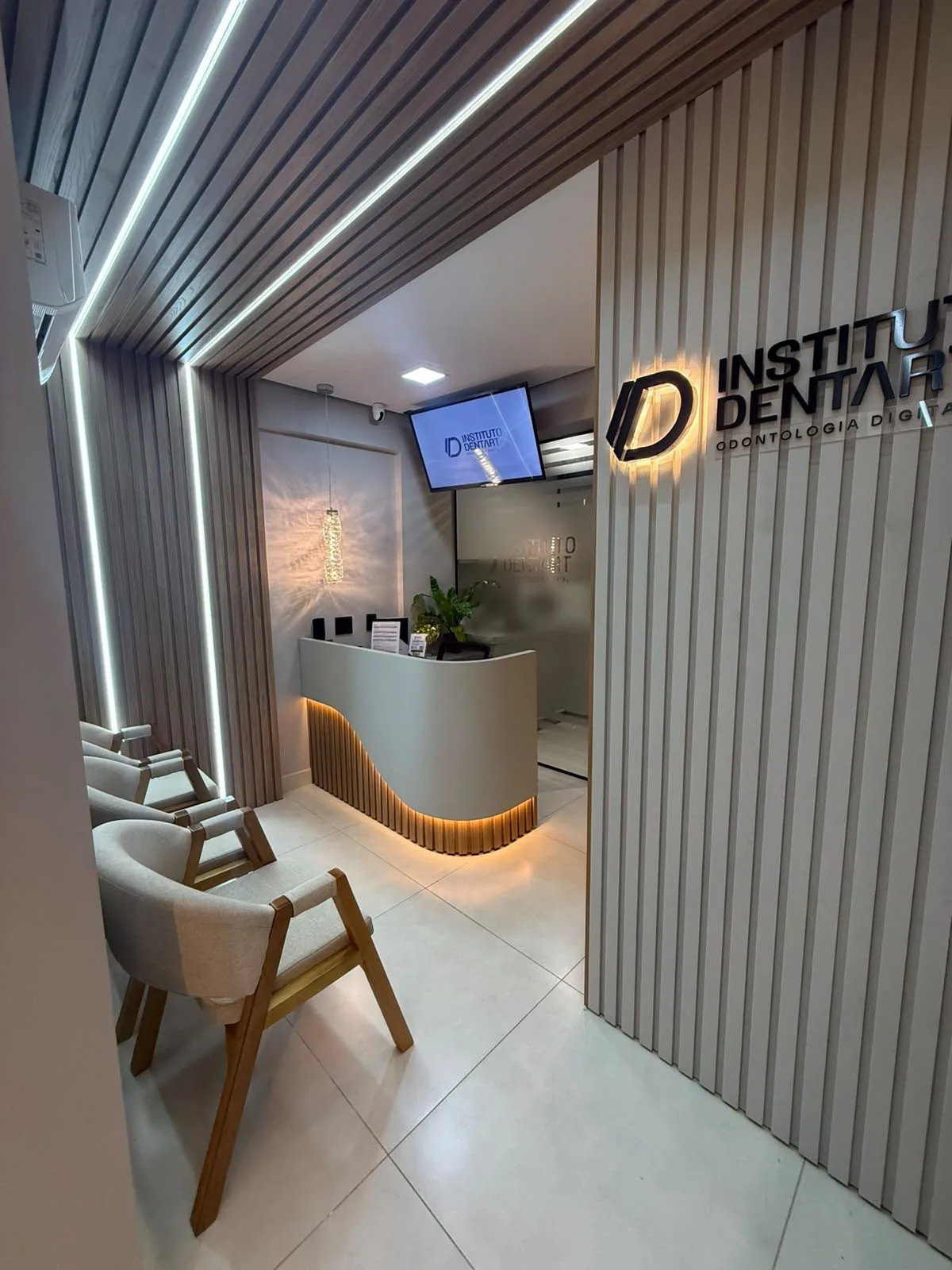 Recepção do Instituto Dentart, com painéis ripados em madeira, balcão iluminado e a logo do instituto na parede.